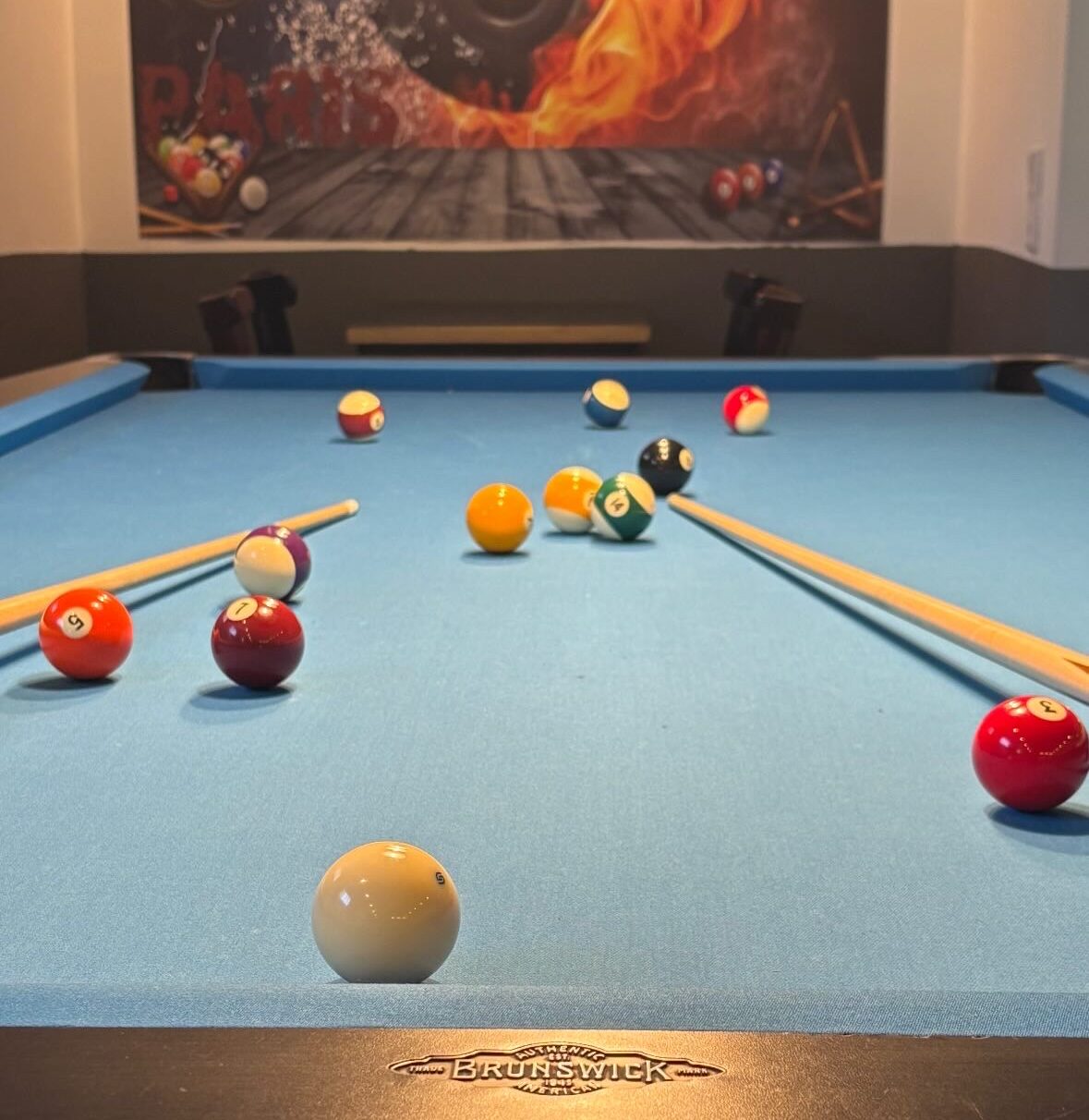 Ein Billardtisch mit bunten Kugeln und Queue auf blauem Filz.